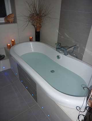 Freestanding roll-top bath against tiled walls