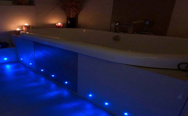 Bath lit by blue plinth lights at night