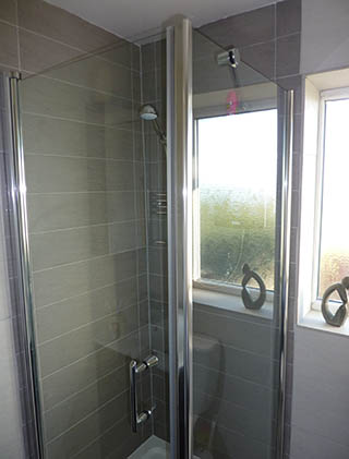 Glass shower enclosure with grey wall tiles