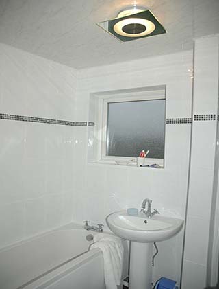 New white bathroom suite with a mosaic border and new ceiling light