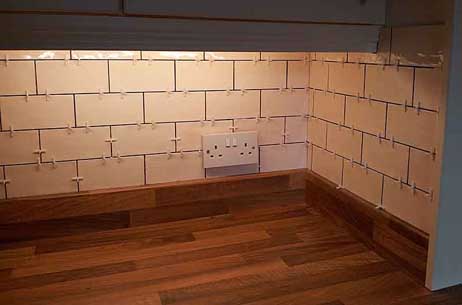 White brick-pattern tiles held with 2mm spacers before grouting