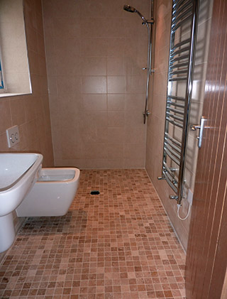 Wet room with a mosaic floor, wall-hung toilet and chrome towel radiator