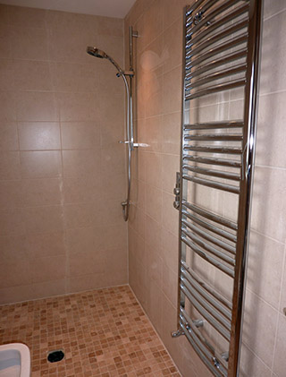 Wet room shower area with mosaic floor and towel radiator