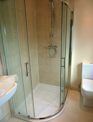 Quadrant shower enclosure with beige wall tiles